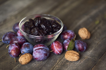 Dried plums - prunes in the bowl on wooden background