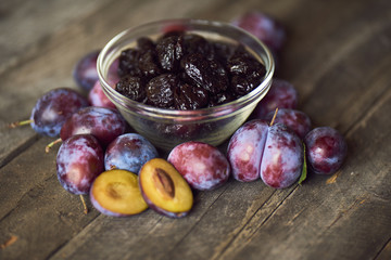 Dried plums - prunes in the bowl on wooden background