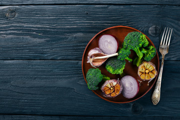 Fresh vegetables on a clay plate. On a wooden background. Top view. Free space for your text.