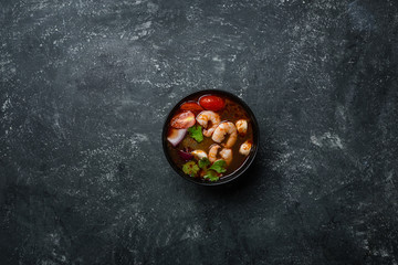 Spicy Thai soup Tom Yam with seafoodon on a vintage colored background. Top view
