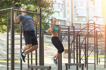Young sporty couple doing exercise on playground