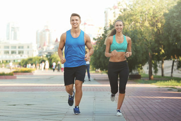 Young sporty couple running in green park