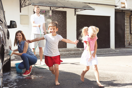 Adorable children playing while parents washing car outdoors