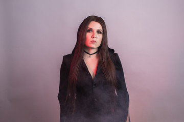 Gorgeous brunette with dark makeup. Halloween witch with smoke in studio