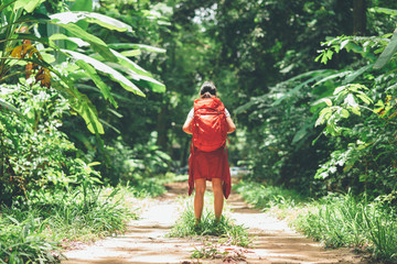 Back view of Asian woman traveler with backpack standing on the path in forest