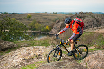 Cyclist in Red Riding the Bike on Autumn Rocky Trail. Extreme Sport and Enduro Biking Concept.