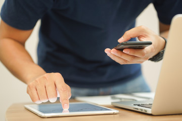 close up trader man hand swipe on tablet with stock graph dashboard and holding smartphone for...