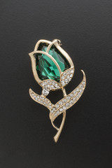 gold brooch rose bud with emerald and diamonds isolated on black - 177679709