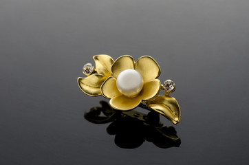gold brooch flower with pearl isolated on black