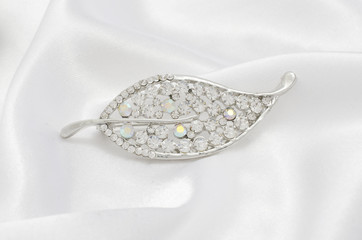 silver brooch leaf with diamonds isolated on silk