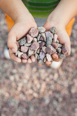 Baby holding stones in hands in nature