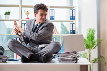 Businessman sitting on top of desk in office