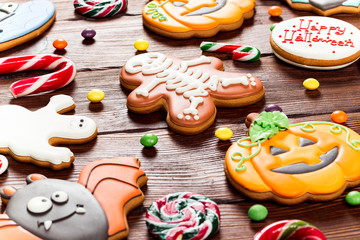 Halloween gingerbread, candy, autumn leaves and berries on a wooden table. Happy Halloween Beautiful festive background