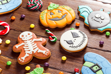 Halloween gingerbread, candy, autumn leaves and berries on a wooden table. Happy Halloween Beautiful festive background