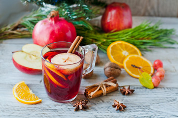 Obraz na płótnie Canvas Mulled wine and fruit, Christmas decor on a wooden background. Celebratory cocktail in a glass glass. Close-up