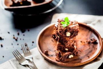 homemade dark chocolate brownies slices and mint on wood table with copy space.