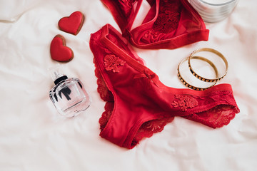 Woman's sexual red lingerie on white bedsheets from above. Copy space. Beauty, fashion blogger concept