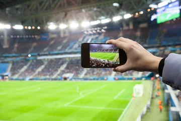 Foto op Canvas Fan hand with smartphone photographing footbal game © Kekyalyaynen