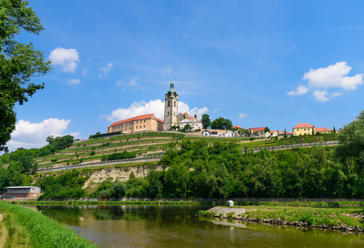 The historic Mělník castle and church tower of St. Peter and Paul at the confluence of the Vltava (Moldau) and Labe (Elbe) rivers on sunny early July afternoon in 2017.