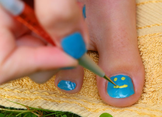 teenager girl hand with enamel laque brush pedicure her toes foot with creative smile pattern