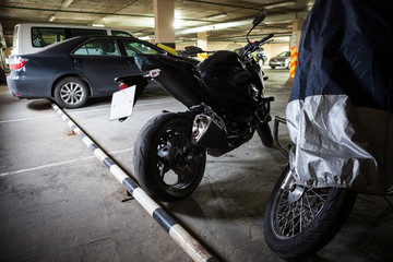 Two motorcycles standing in parking area with one cover tent, overwintering in northern country