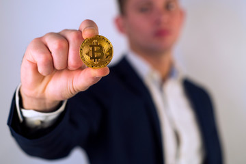 Golden Bitcoin in a man hand, Digitall symbol of a new virtual currency