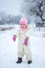 Full length portrait of little girl playing on snow in winter park.