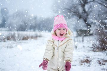 Fototapeta na wymiar Cheerful little girl playing on snowy winter day.