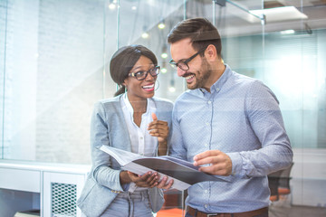 Through glass view of two happy business people having meeting in office.
