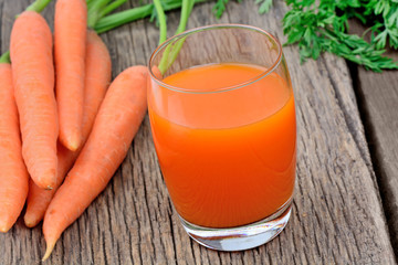 Carrot juice in a glass on wooden table
