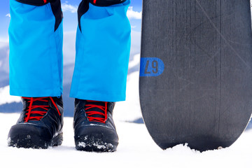 Man standing in snowboarder boots on the top of the alps mountain with snowboard