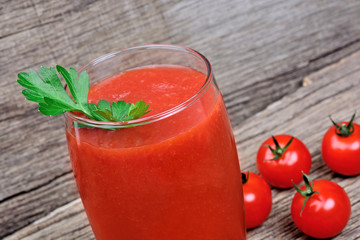 Glass of fresh tomato juice on rustic wooden background