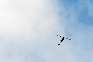 The helicopter on the blue sky with clouds