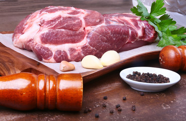 Raw pork neck chop meat with parsley herb leaves, grinder for spices and garlic on a stone background. Ready for cooking.