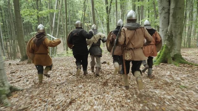 Warriors of Vikings are running in the forest on the battle.