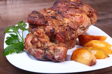 Juicy pork neck chops are grilled with potatoes on a white plate.