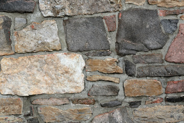 Stonework wall in rows with mortar in many colors