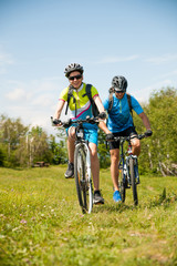 Fototapeta premium ACTIVE Young couple biking on a forest road in mountain on a spring day