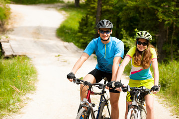 ACTIVE Young couple biking on a forest road in mountain on a spring day