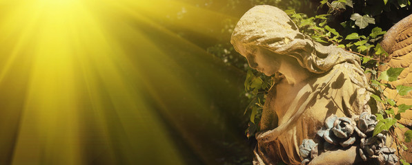 Majestic view of statue of golden angel illuminated by sunlight against a background of dark...