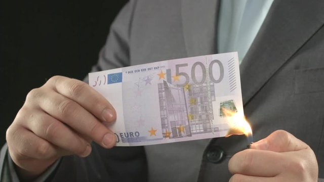 Male in suit burning euro bill, money devaluation, inflation and crisis, closeup