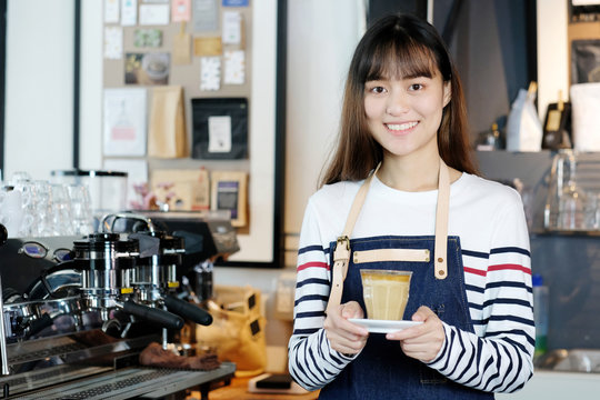 Young asian women Barista serving coffee cup with smiling face at cafe counter background, small business owner, food and drink industry concept