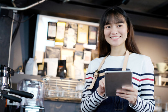 Young asian woman, barista, using tablet to get coffee order at cafe counter background, food and drink concept