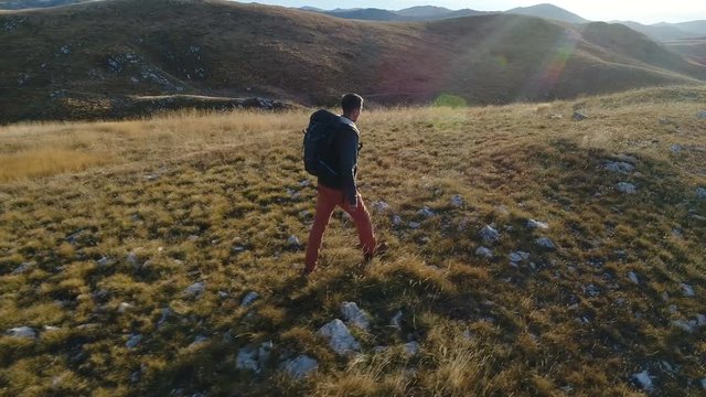 tourist with a backpack walks among the hills