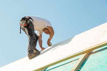 Carpenter roofer at work with wooden roof construction.