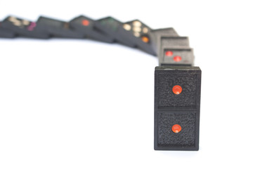 Fototapeta premium Row of old black color dominoes with colorful dot pieces on white floor background.