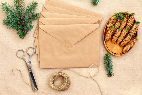 Christmas gifts and letters handmade, and everything necessary for them. Envelopes of Kraft paper, scissors, spruce cones and jute cord. The view from the top. The concept of simplicity