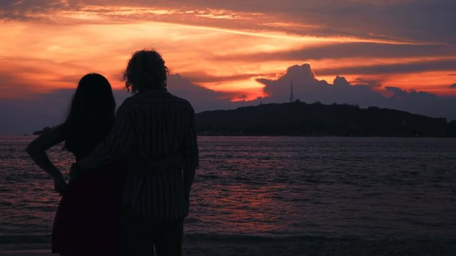 Cople hugging silhouettes on beach in front of ocean sunset and island. Shot with Sony a7s and Atomos Ninja Flame in Gili Meno, Indonesia.