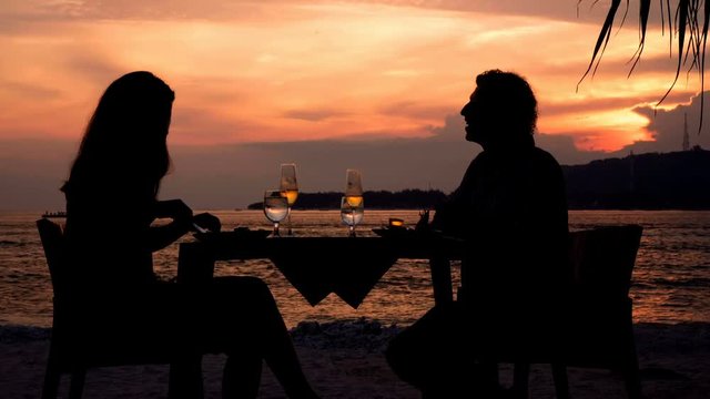Couple silhouettess having romantic dinner on beach at sunset. Shot with Sony a7s and Atomos Ninja Flame in Gili Meno, Indonesia.