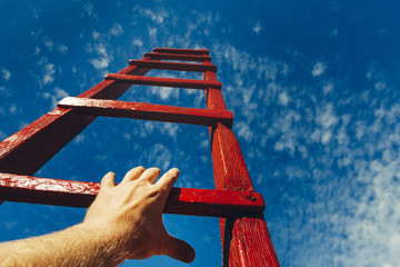 Hand Of Man Reaching For Red Ladder Leading To A Blue Sky. Development motivation Career Growth...